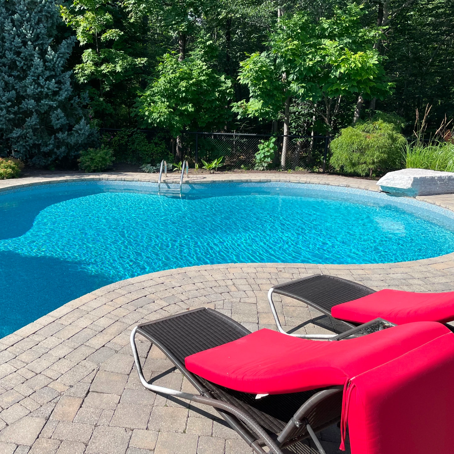 A backyard with a pool and chairs
